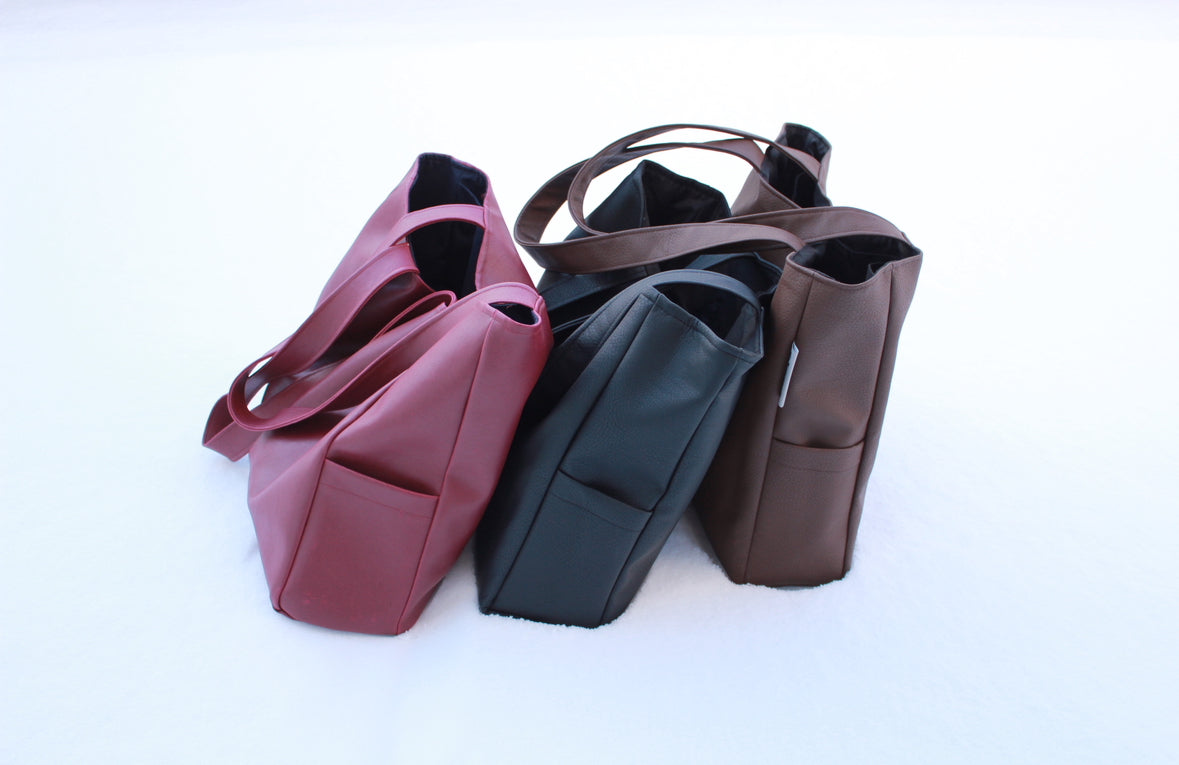 Three handbags in pink, black, and brown on a white background